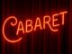Neon Cabaret sign set against red velvet stage curtains